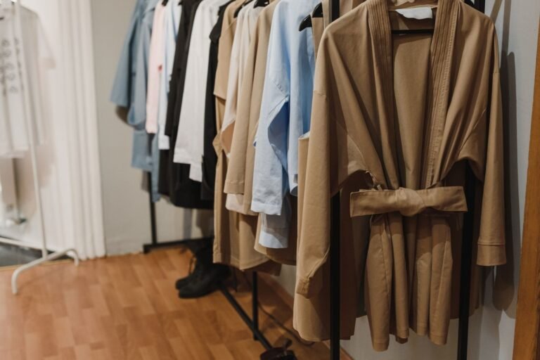 Camel coat and neutral garments on a wardrobe rail — designer resale preparation Sydney