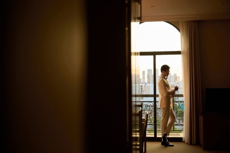 Guest in a cream dinner jacket on a hotel balcony above the city skyline — hotel dry cleaning Sydney CBD