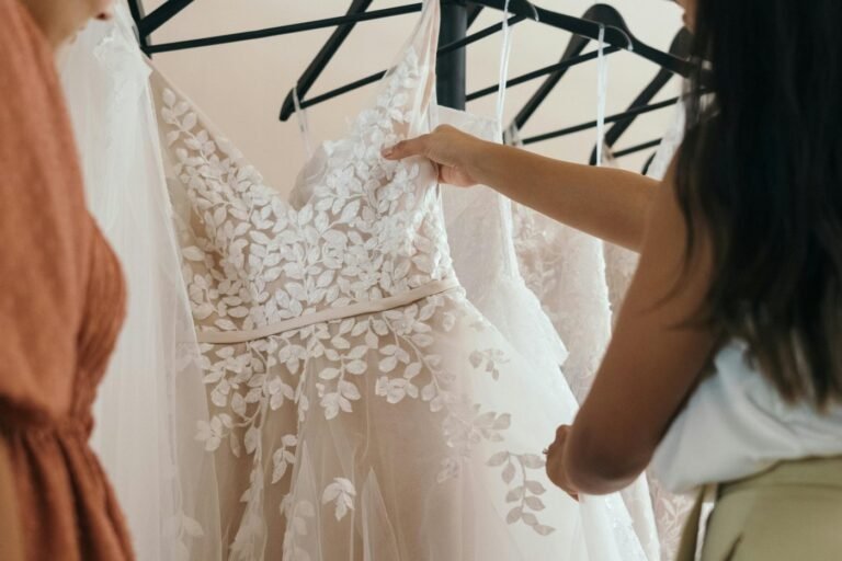 Bride lifting a lace wedding dress from a rail of gowns, wedding dress cleaning cost Sydney
