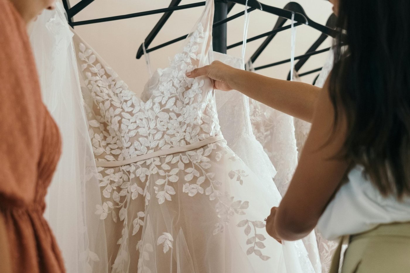 Bride choosing a wedding dress from gowns hanging on a rail, illustrating wedding dress cleaning after the wedding in Sydney